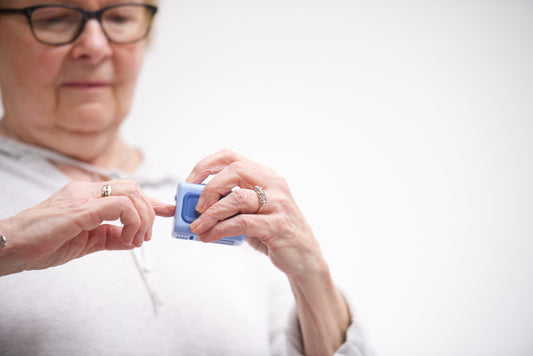 A senior woman against a white background trimming her nails with the adult size Lil Nipper.