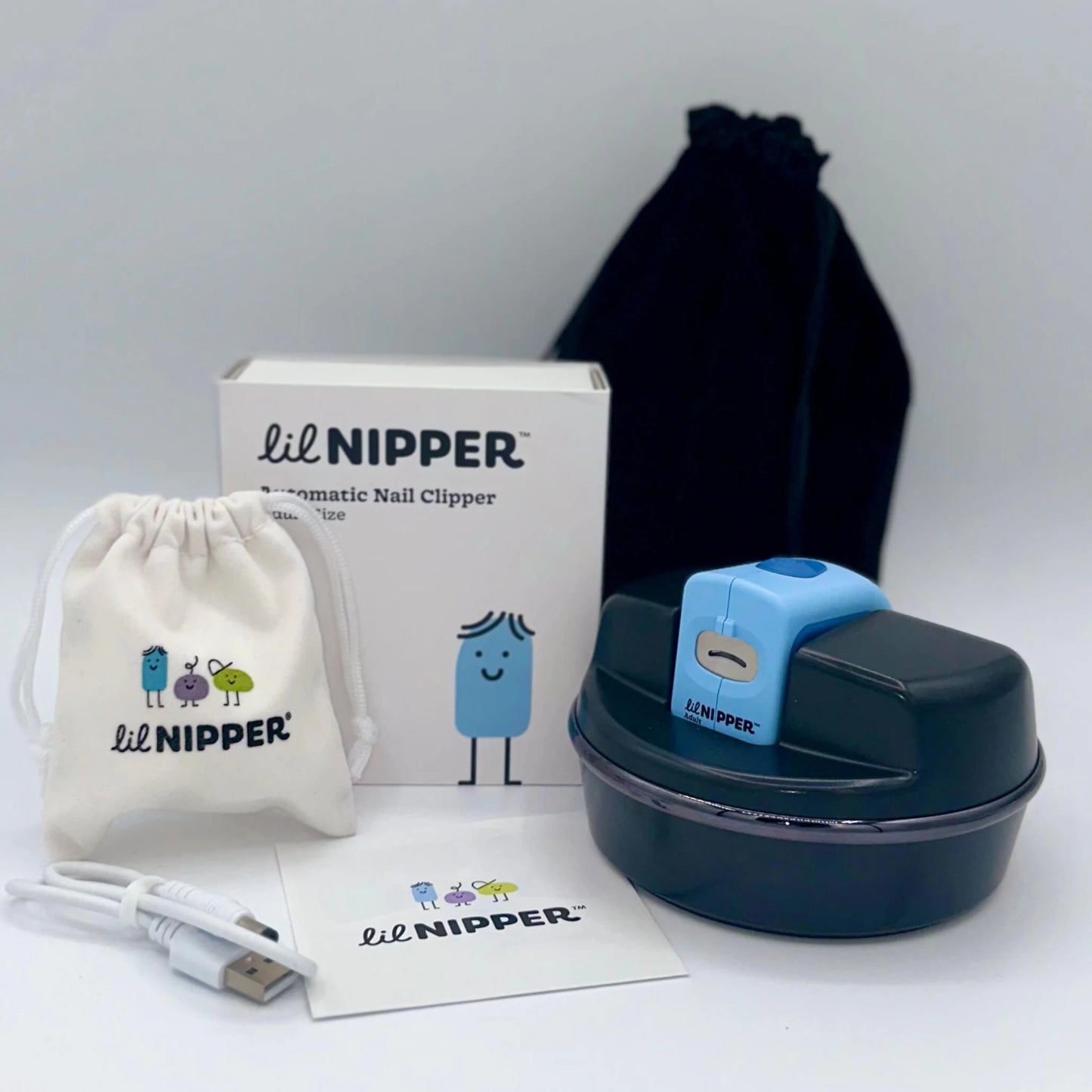 Lil Nipper product packaging with blue adult electric nail clipper and The POD adaptive base. Shows all contents: device, pod, 2 drawstring bags, manual, and USB cable on a white background.