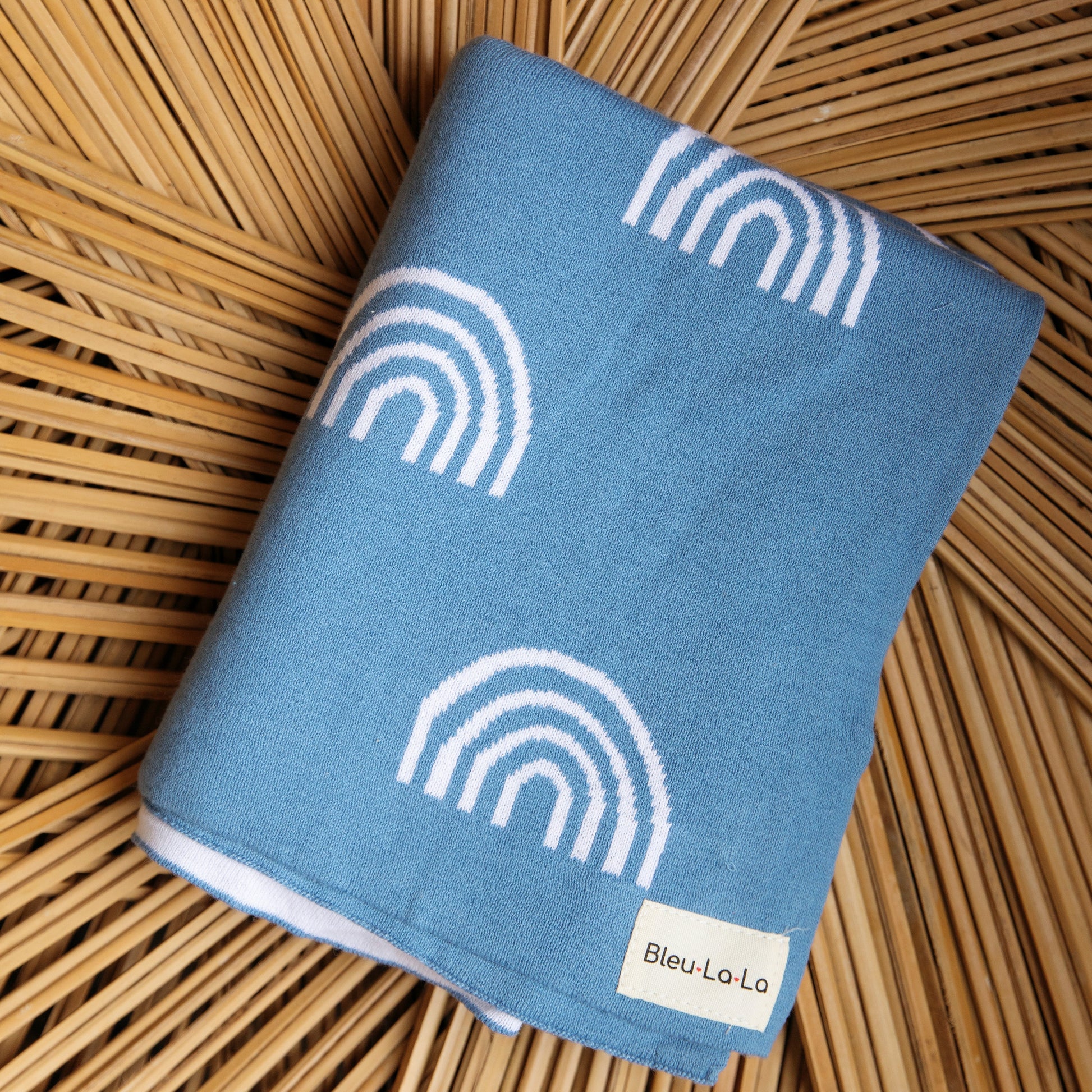 Blue towel with white rainbow patterns on a woven surface