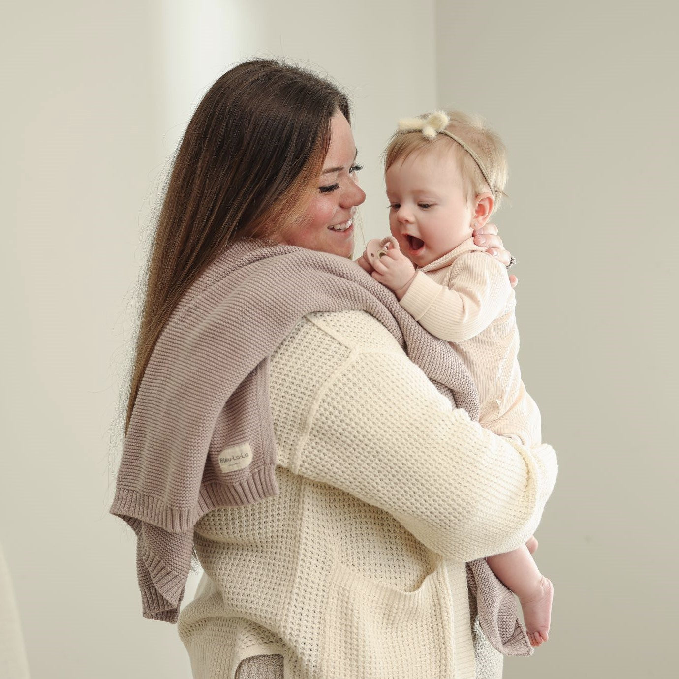 Woman holding a baby against Blue-La-La blanket with a plain background