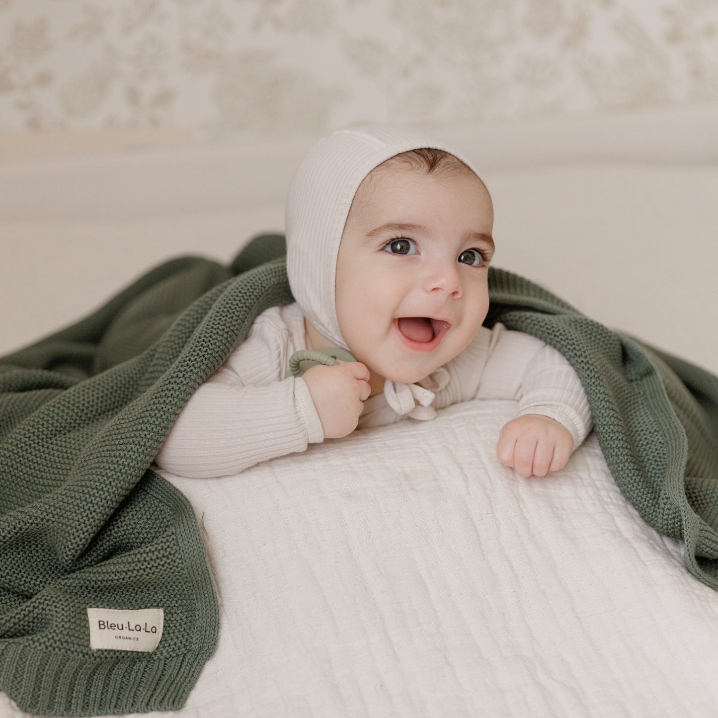 Baby wrapped in a green Blue-La-La blanket with a white background