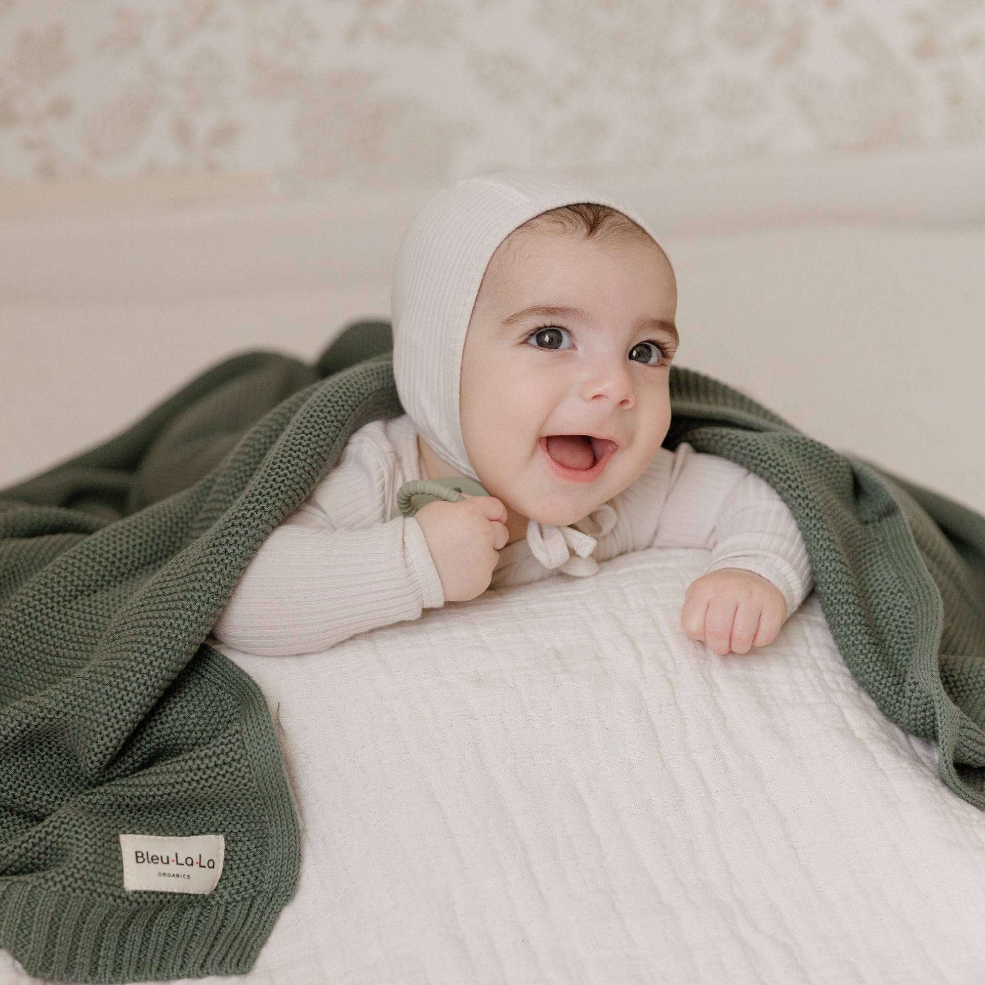 Baby wrapped in a green Blue-La-La blanket with a white background