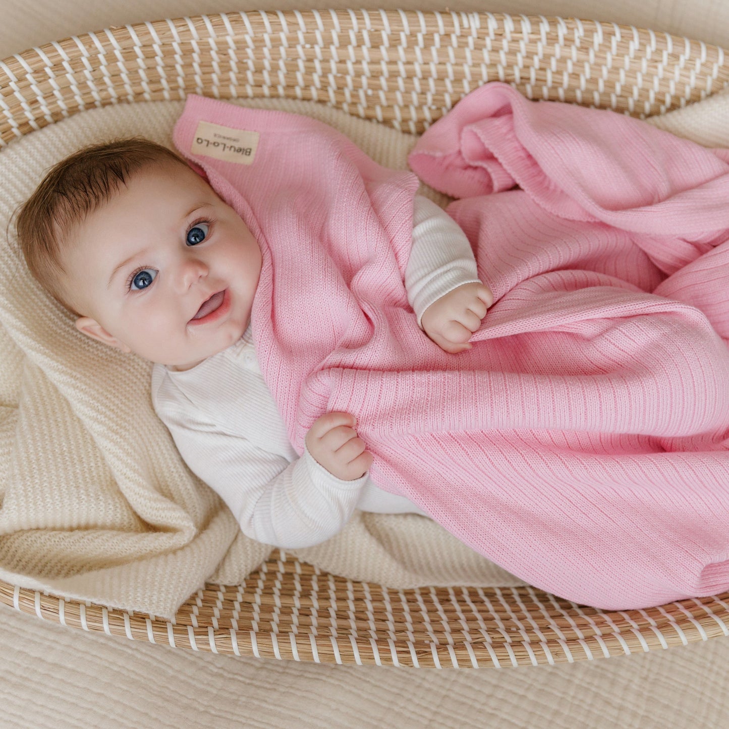 Baby wrapped in a pink blanket, lying in a basket