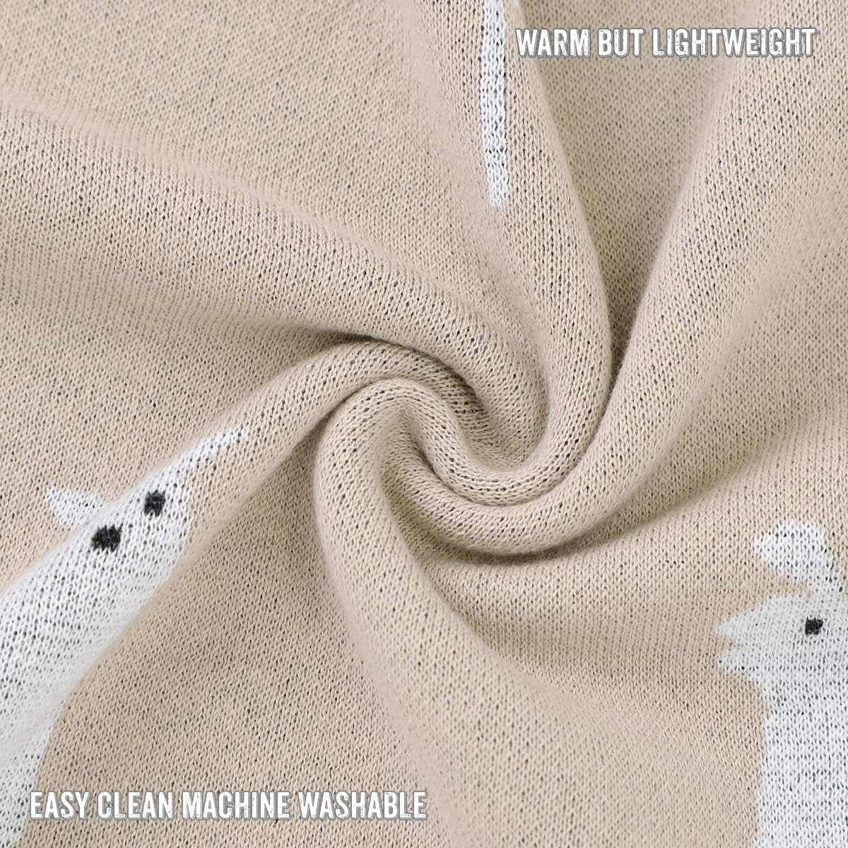 Close-up of beige fabric with embroidered white animals, text indicating warmth and machine washability.