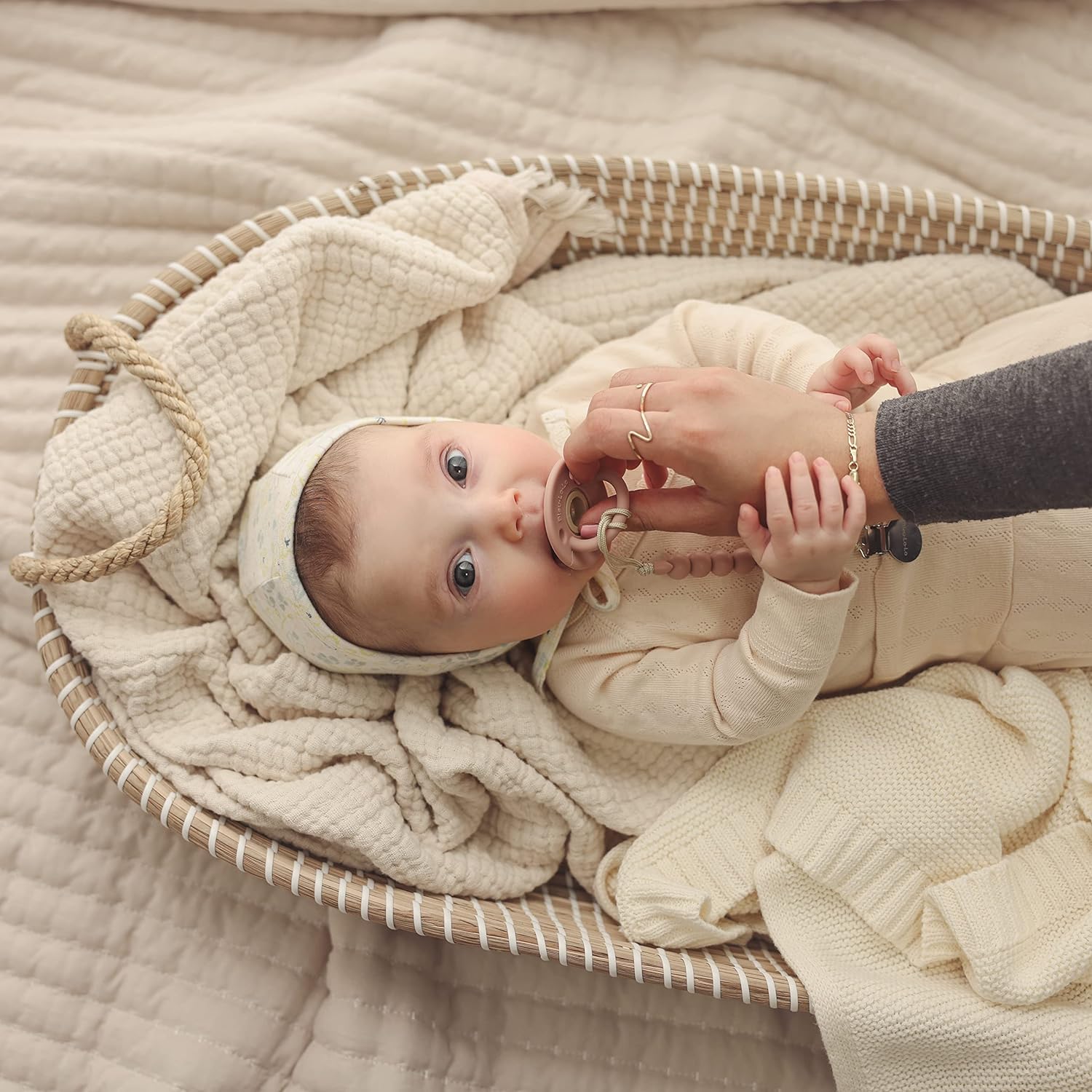 Baby lying in a basket with a Blue-La-La blanket, being held by an adult.