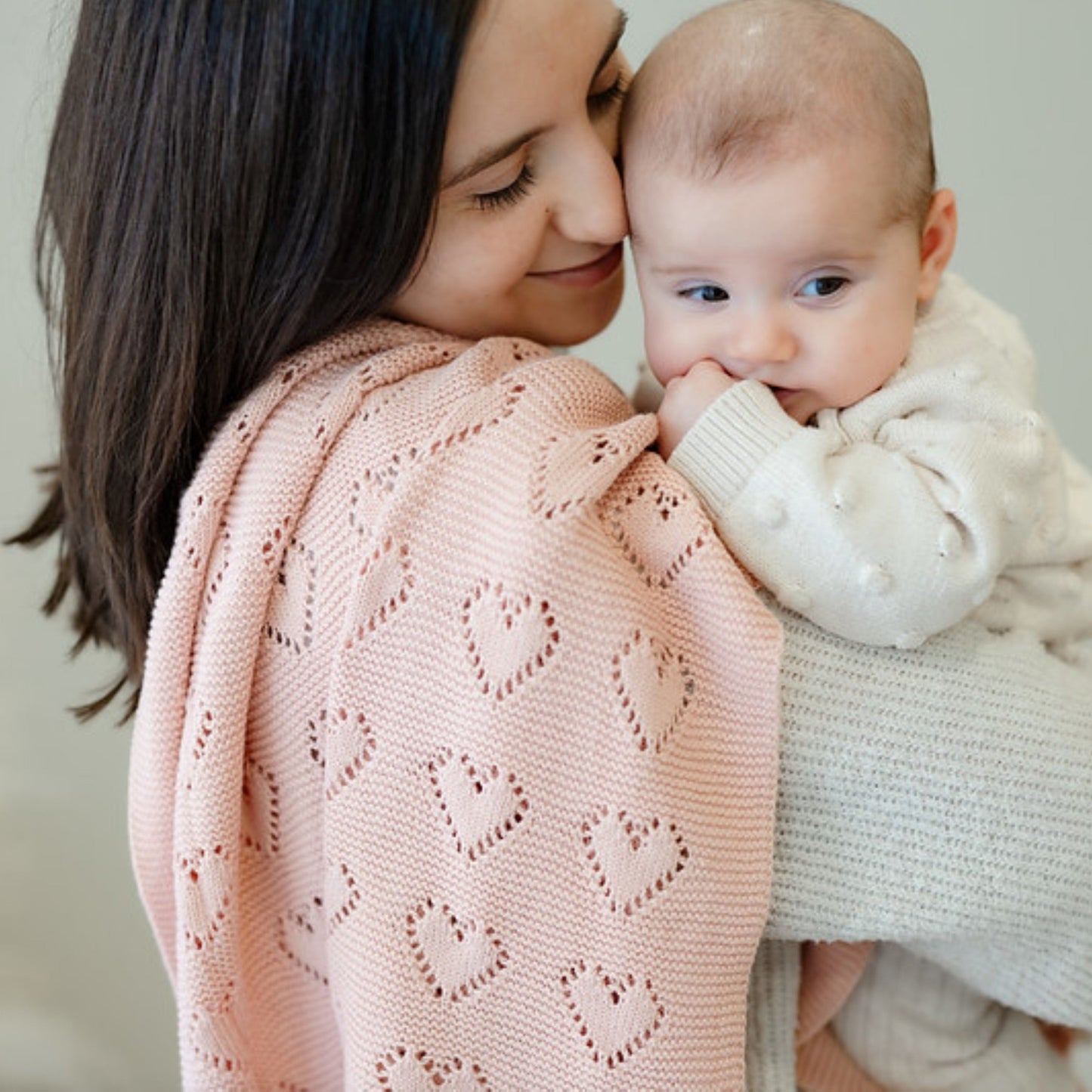 Woman holding a baby wrapped in a pink knitted Bleu-la-la  blanket
