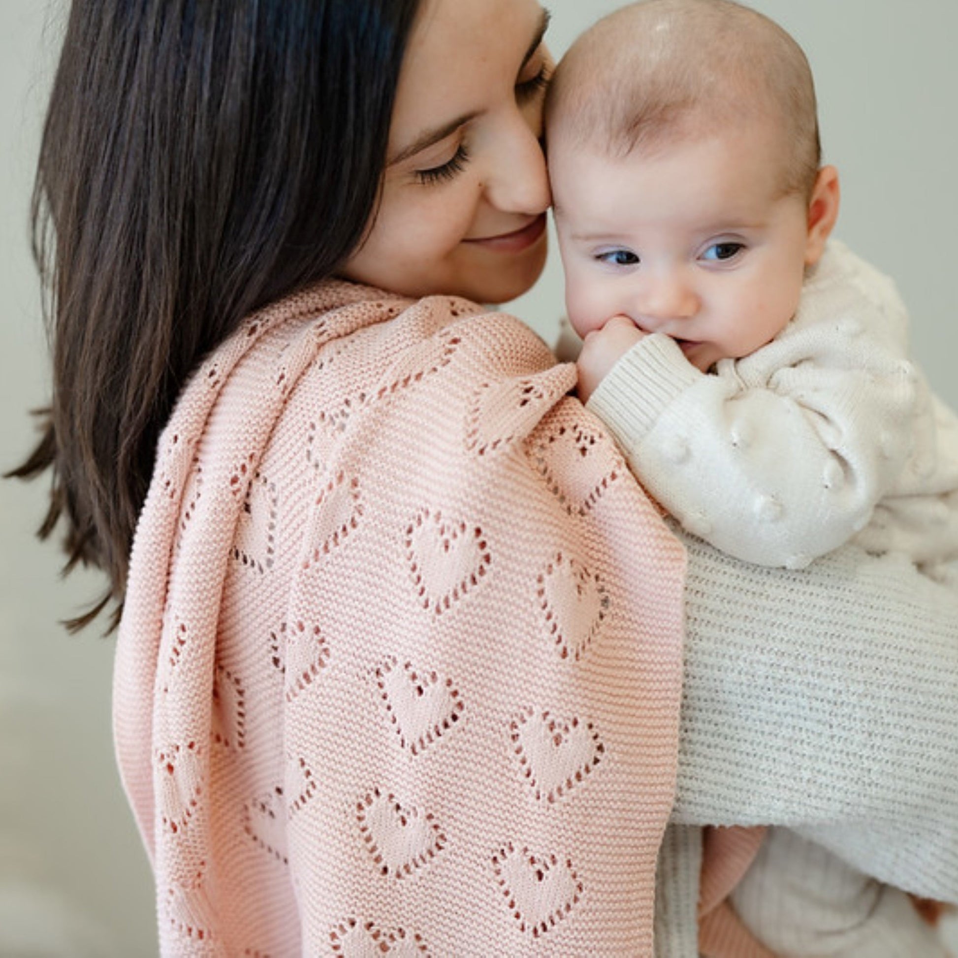 Woman holding a baby wrapped in a pink knitted Bleu-la-la  blanket