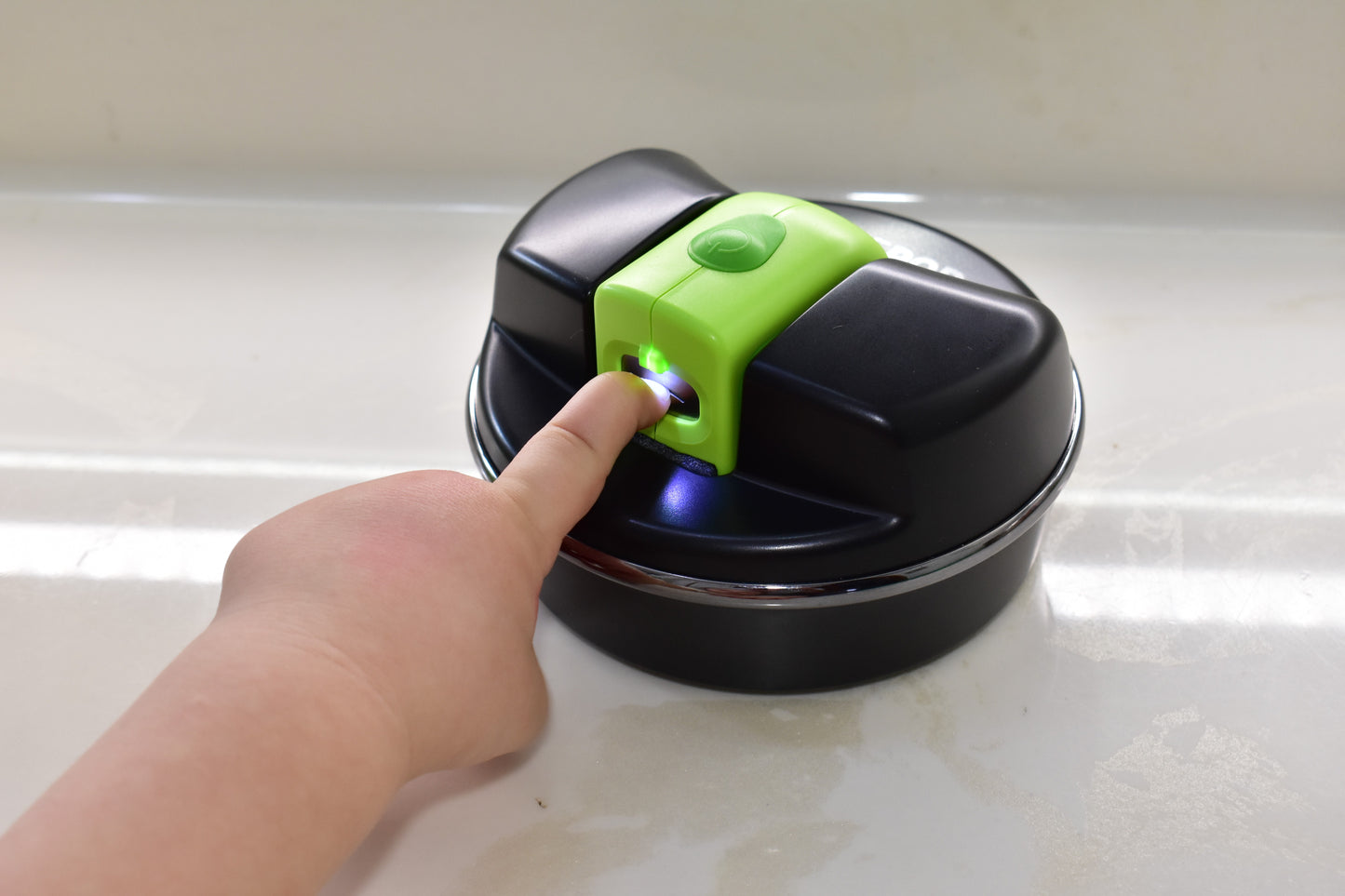 A young child is using the Pod with a green child size Lil Nipper. The bright LED light is shining on the little finger and their nail is inside the safety slot being trimmed.