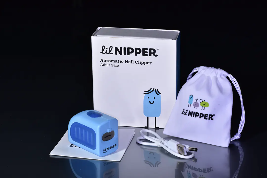 The Lil Nipper Adult clipper, packaged in a sleek and modern box, perfect for gifting. Includes a carrying bag, charging cable, cool box, manual and device.
