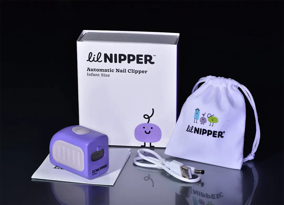 Image with all the components of the Lil Nipper. Shows a carrying bag, device, charging cable, cool modern box with a character on front, instruction manual.