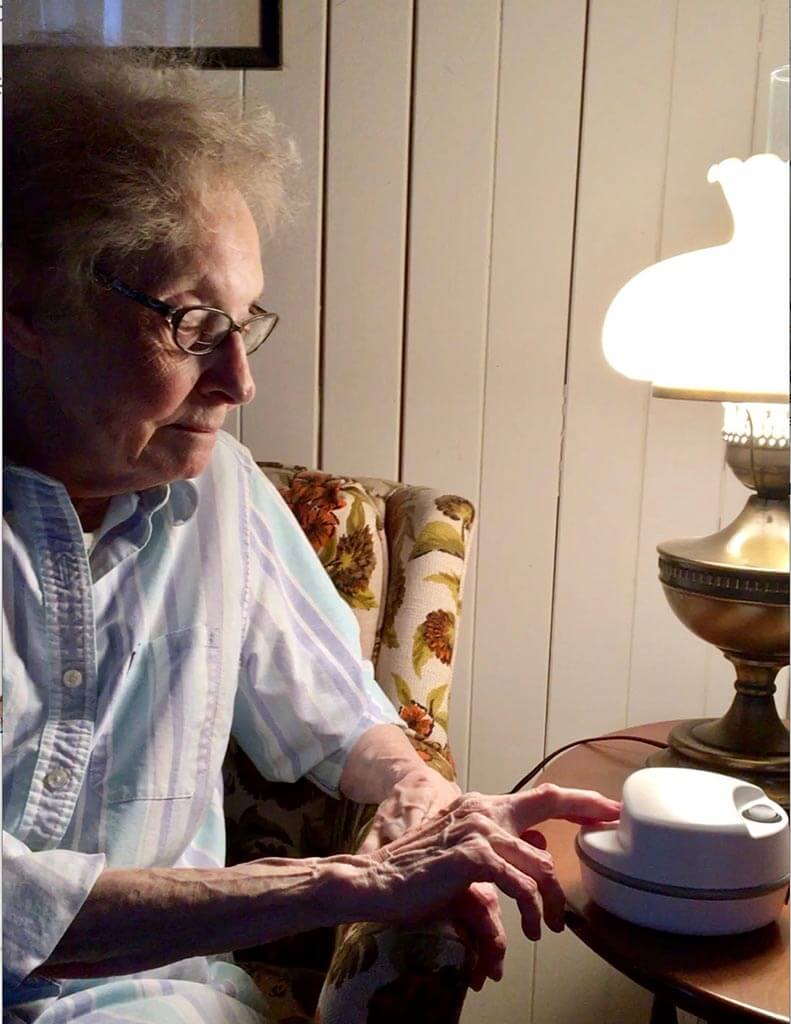A senior using the ClipDifferent Pro. She's sitting on her chair and the Pro is resting on the table.