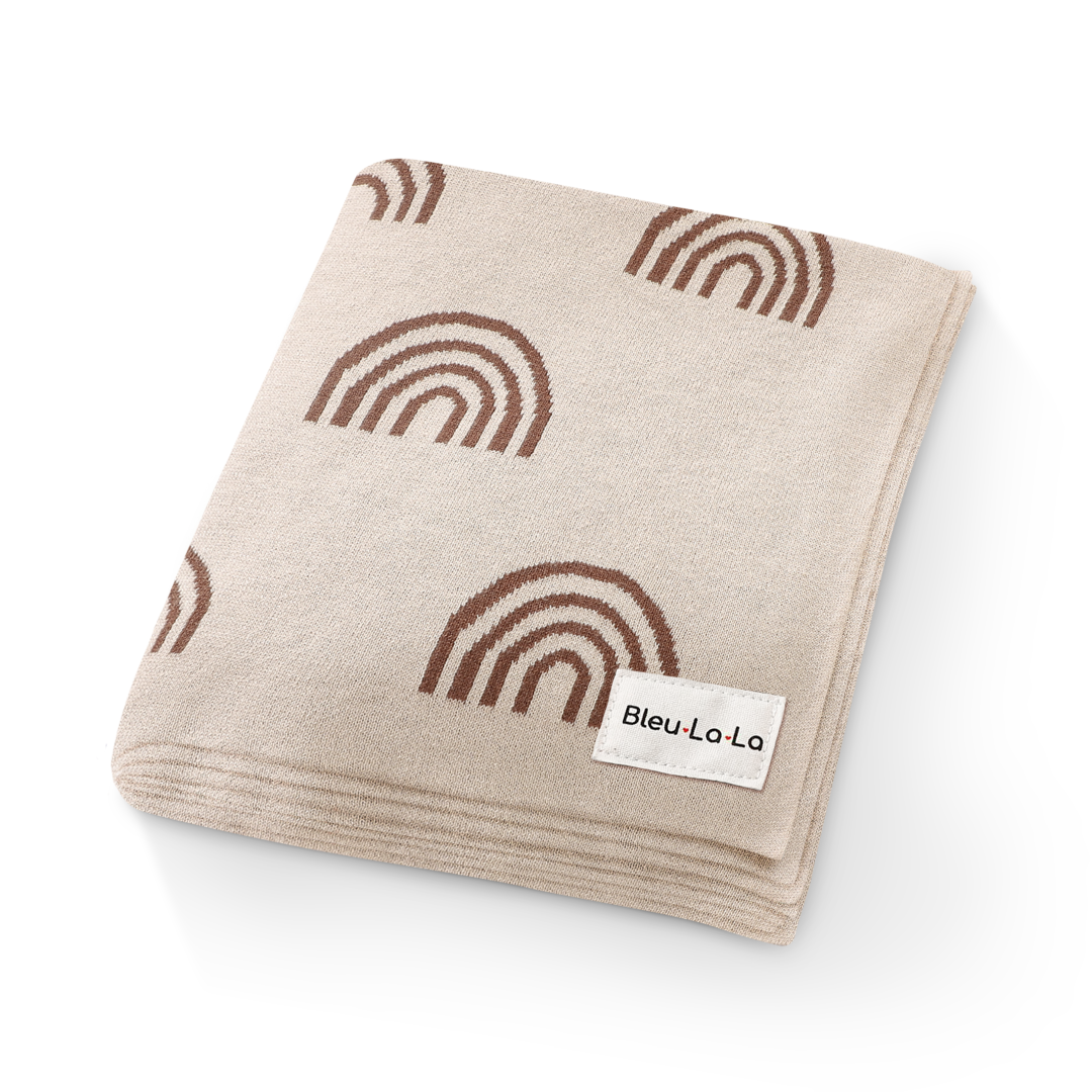 Beige blanket with brown rainbows and a visible brand label on a white background