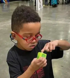 A young African American boy with red glasses using Lil Nipper Child size.