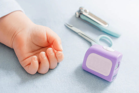 Baby hand with a Lil Nipper, scissors and nail clipper