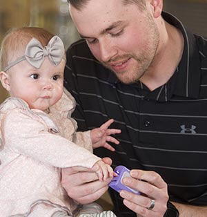 Dad trimming infants fingernails with Lil Nipper