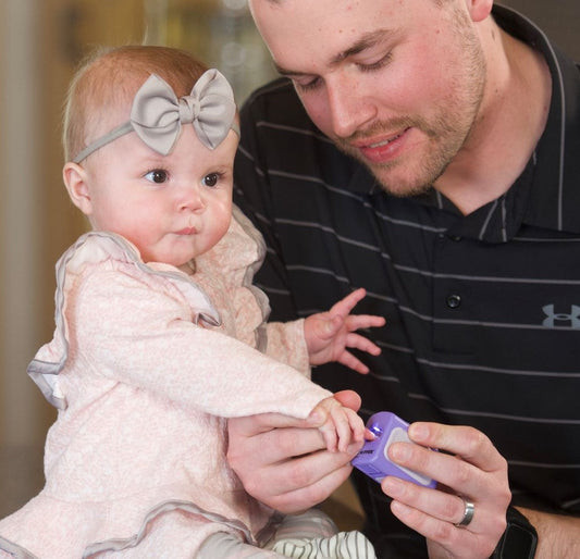 An adult's hand gently holding the Lil Nipper Infant clipper, demonstrating its ergonomic design and ease of use for parents.
