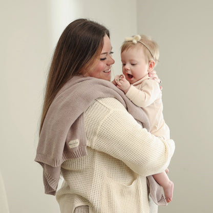 Woman holding a baby against Blue-La-La blanket with a plain background