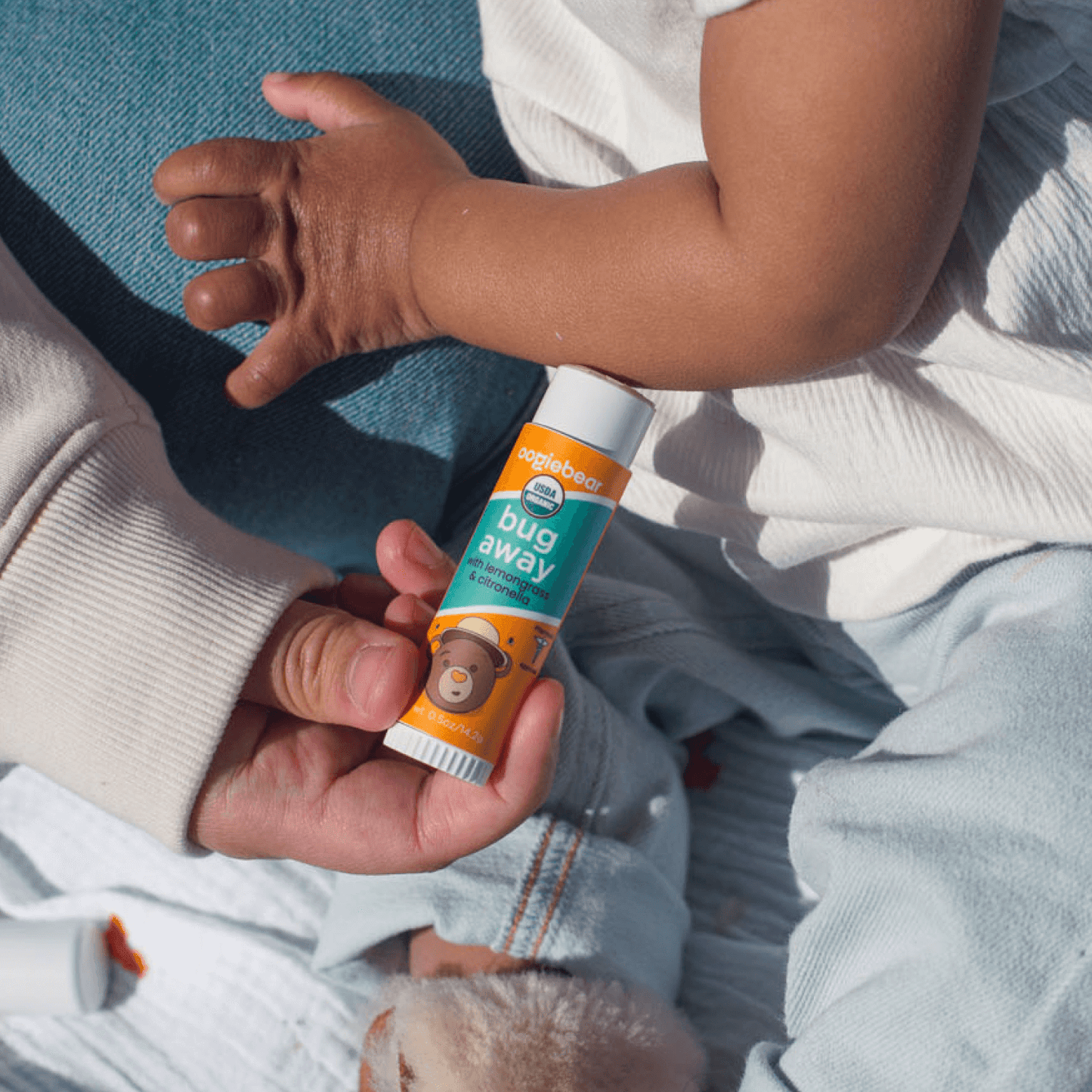 e:
Parent applying oogiebear Bug Away Balm to baby's arms and legs for bug protection