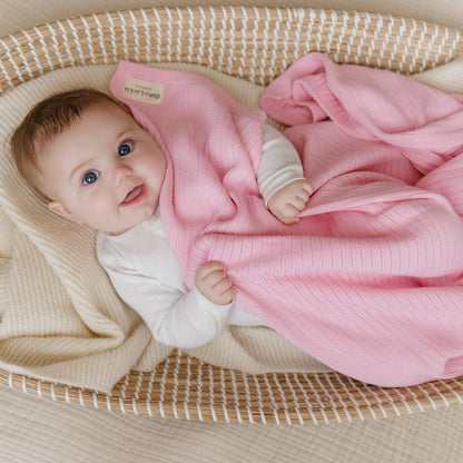 Baby wrapped in a pink blanket, lying in a basket 