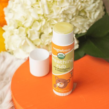 ooriebear breathing rub with the cap off on an orange surface with white flowers in the background