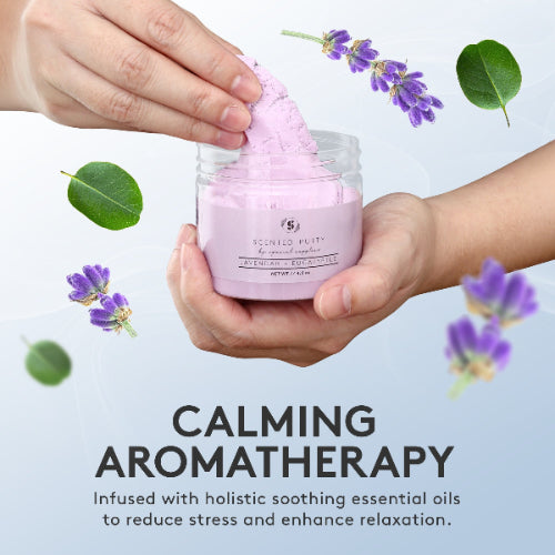 Person holding a jar of pink putty with lavender flowers and leaves on a light gray background, promoting calming aromatherapy.