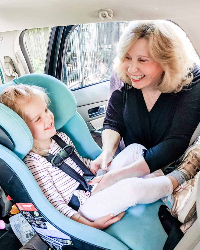 Woman adjusting a child's car seat in a vehicle