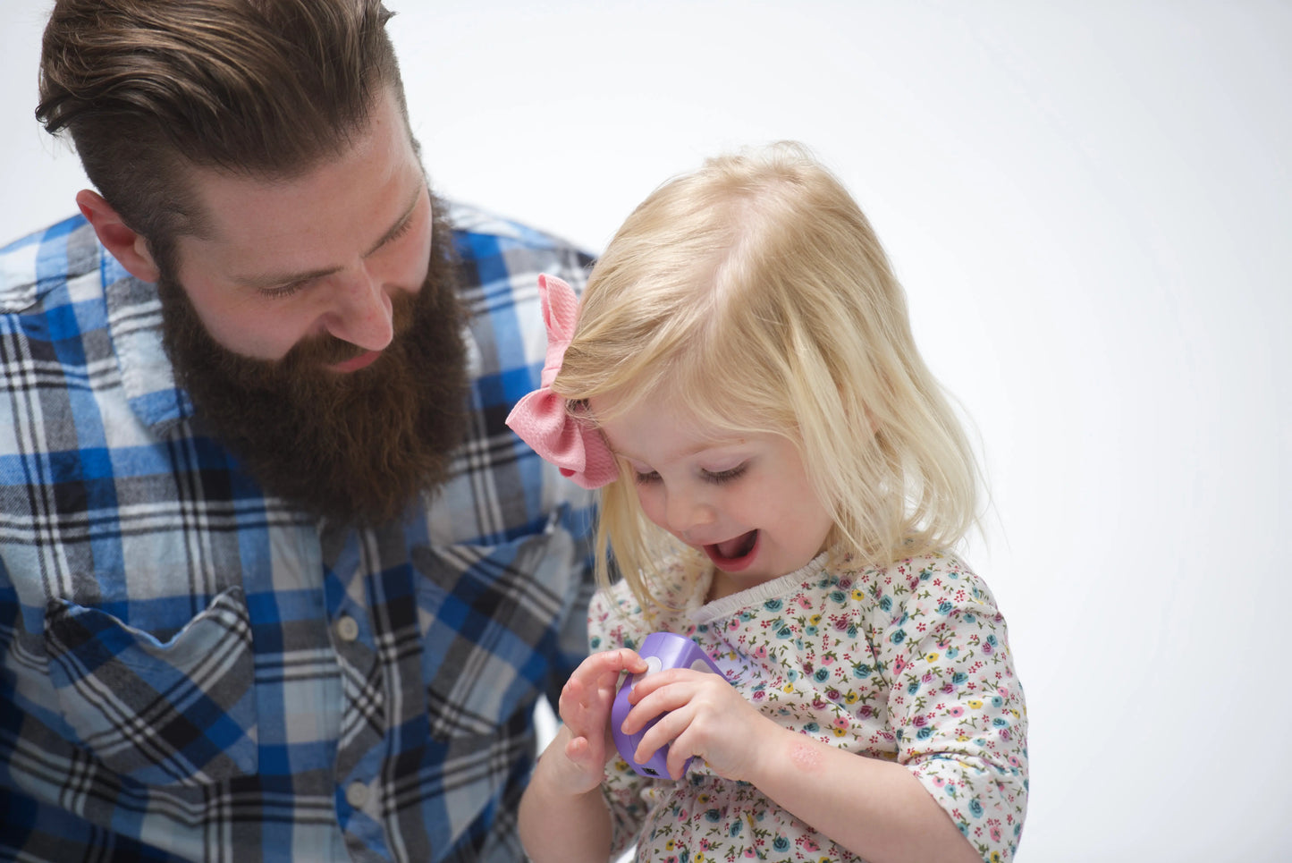 Father teaching young daughter to use purple Lil Nipper infant electric nail clipper for safe independent nail care. Little girl is happy and having fun!