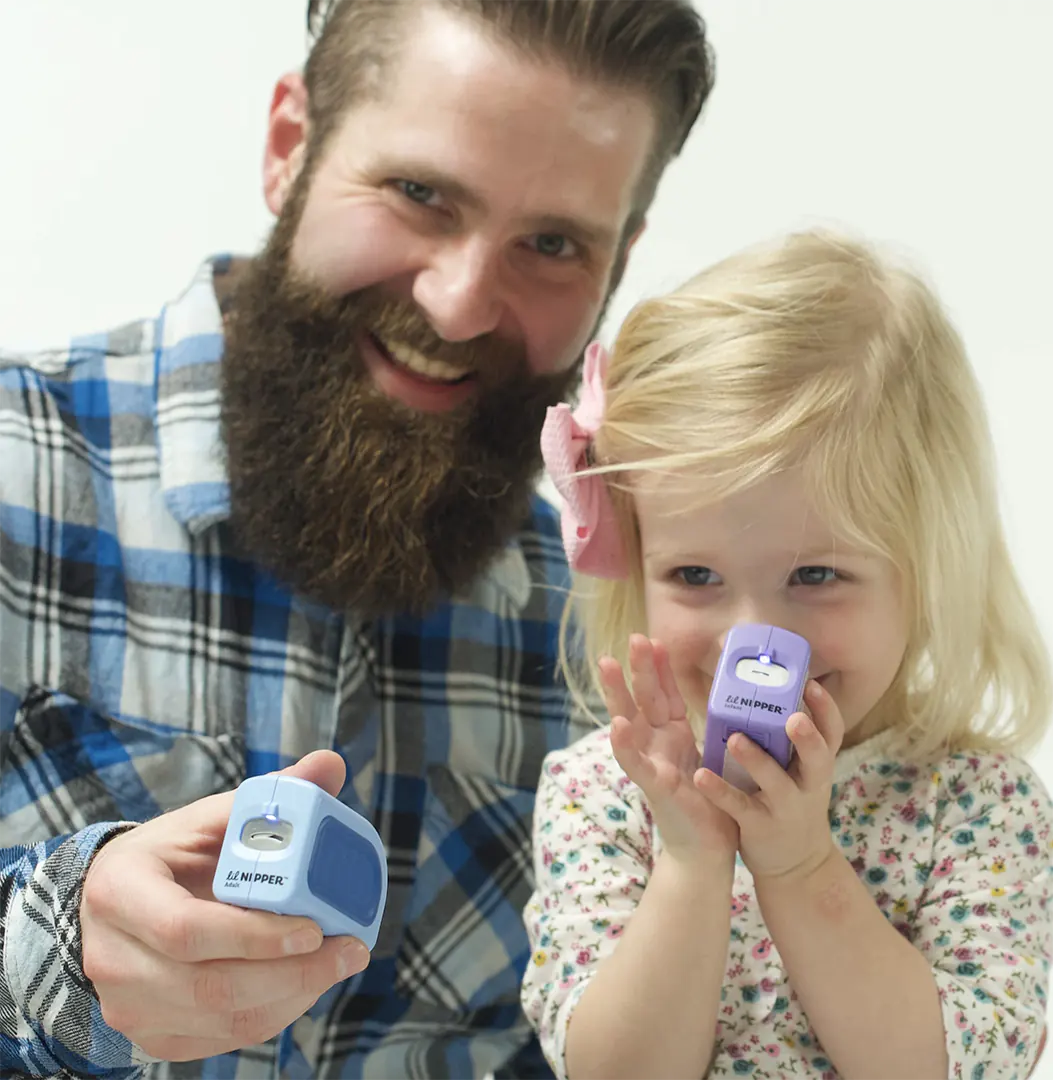 A toddler and her dad both holding Lil Nipper electric nail clippers. Both smiling and having fun.