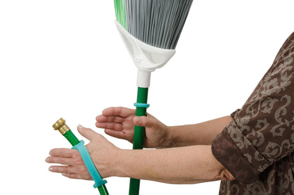 Person holding a broom with a green EazyHold grip tool wearing a brown patterned shirt.