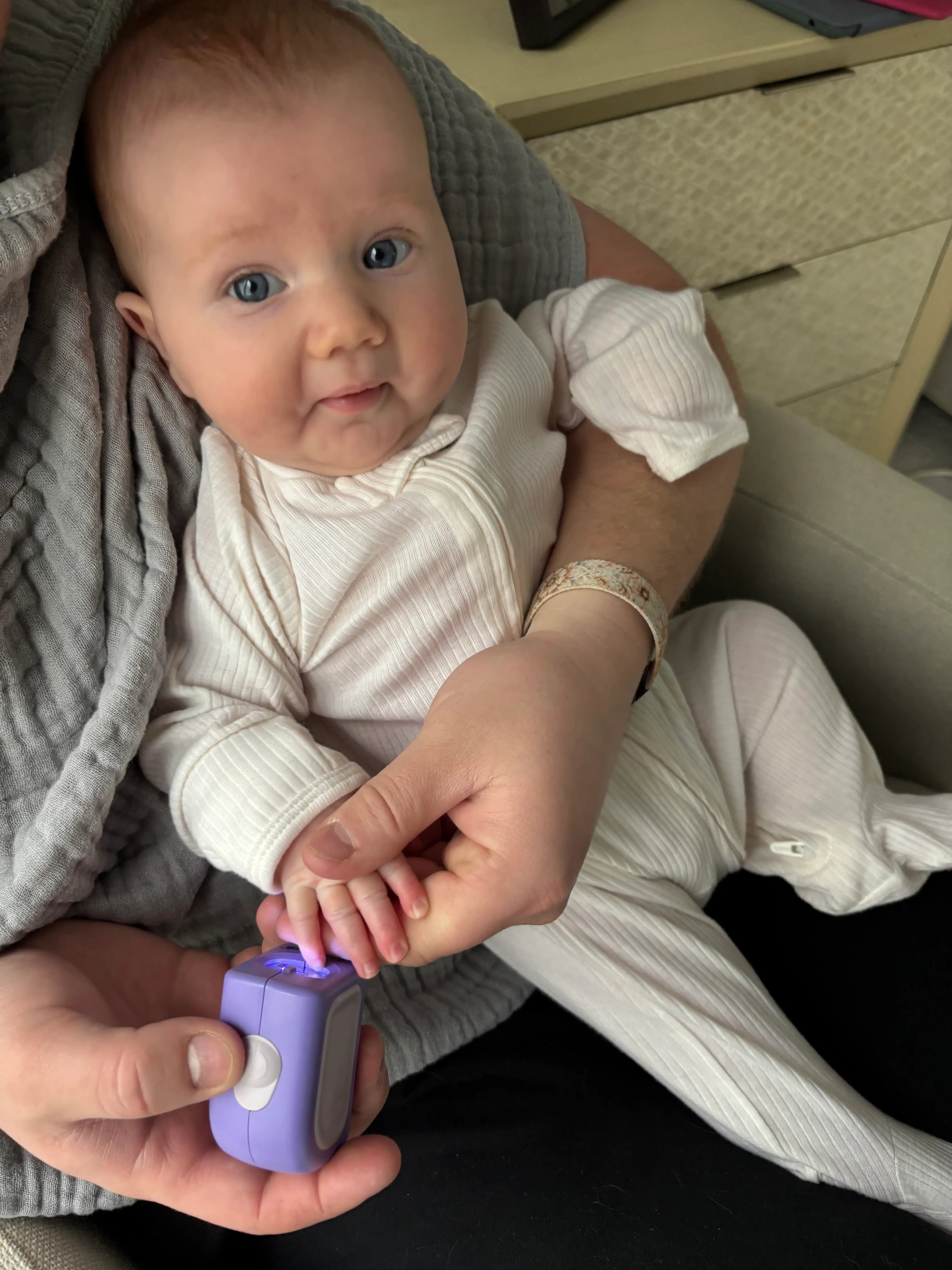 Baby interacting with a purple Infant size Lil Nipper held by an adult