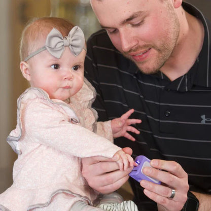 An adult's hand gently holding the Lil Nipper Infant clipper, demonstrating its ergonomic design and ease of use for parents.