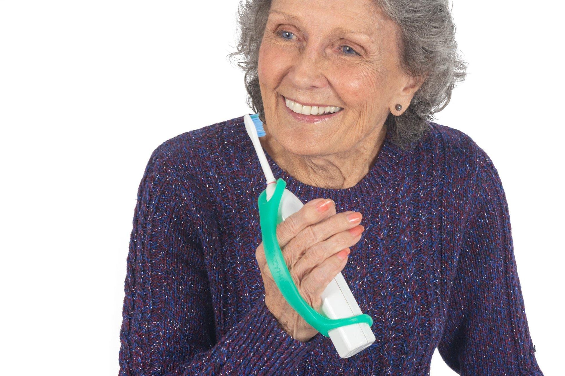 Woman holding a green EazyHold grip tool around a white toothbrush with a white background.
