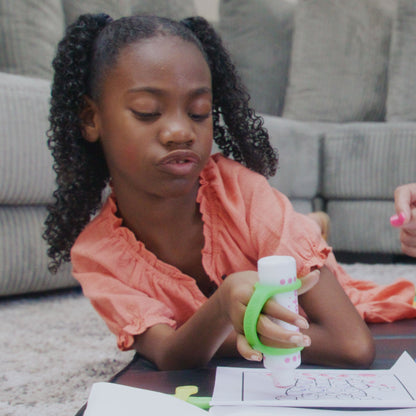 Young girl coloring using EazyHold grip tool with a dotter in a casual indoor setting.