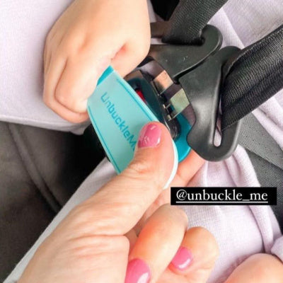 Hand using a 'Unbuckle Me' tool to release a car seat belt.