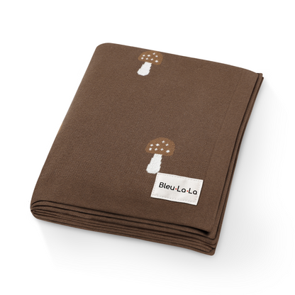 Close-up of luxury brown knit mushroom swaddle blanket showing soft texture and mushroom details