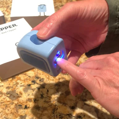 A woman's hands using the Lil Nipper Adult clipper in blue color. Bright LED shines on her nail. 